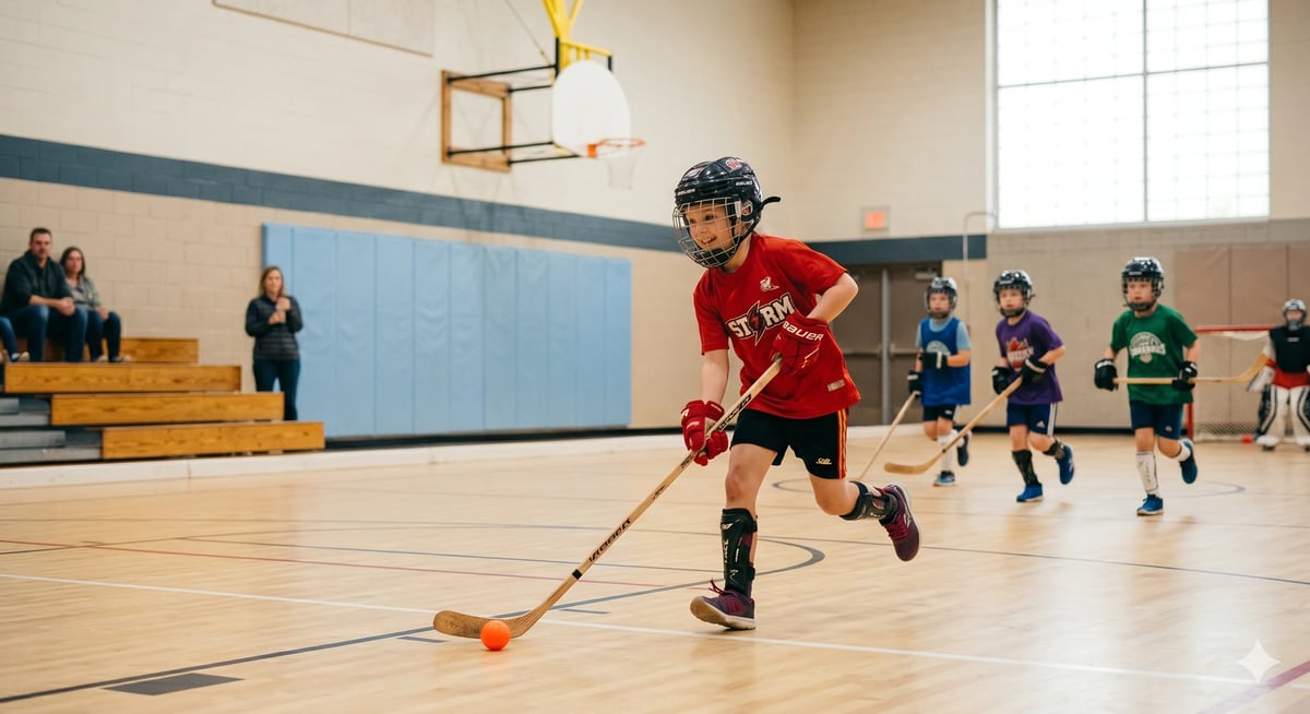 Child in red shirt playing floor hockey with stick and puck in school gymnasium with other young players and coaches in background